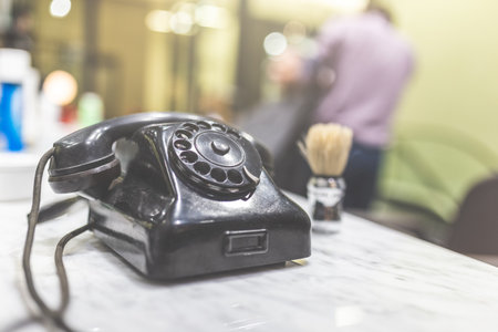 Retro telephone and shaving brush on table at barber shop. Hair salon appointment scheduling concept.の写真素材