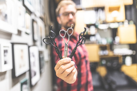 Close up of fashionable barber holding various professional scissors at barbershop.の写真素材