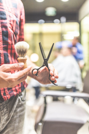 Close up of fashionable barber holding scissors and brush for shaving beard.の写真素材