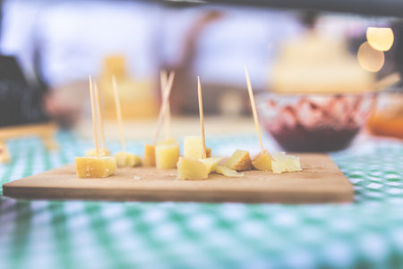 Close up of small cheese sample pieces with toothpicks on wooden cutting board.の写真素材