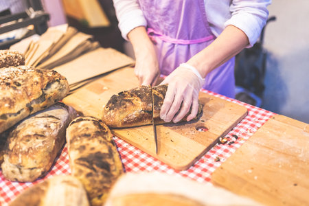 Close up of baker cutting whole grain bread.