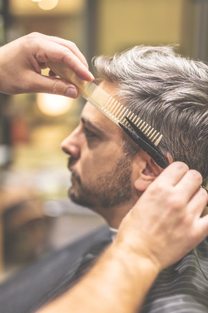 Barber cutting and modeling hair with scissors and comb.の写真素材