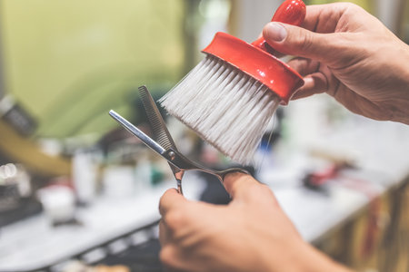 Hairdresser cleaning scissors with brush at barbershop.の写真素材