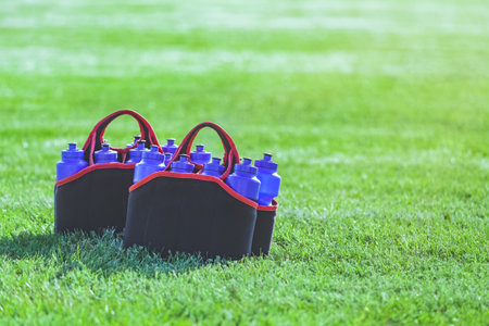 Sport bottles of fresh water energy drink on football rugby field grassの写真素材