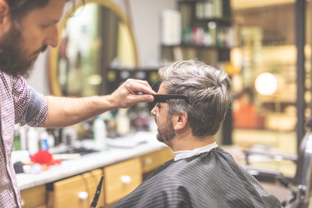 Barber cutting and modeling hair with scissors and comb.の写真素材