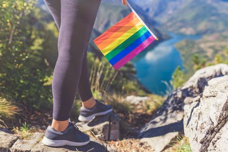 Close up of woman holding colorful rainbow lgbt flag against beautiful nature canyon valley. Freedom concept.の写真素材