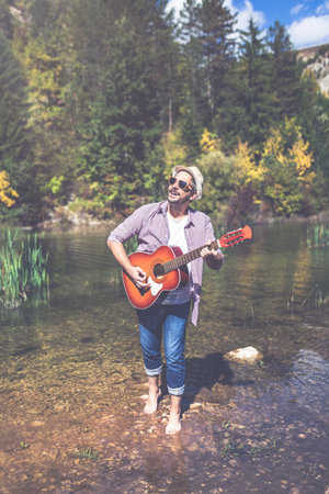Modern man with acoustic guitar in nature.の写真素材