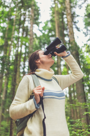 Bird watching traveler using binoculars in forest. Exploration concept.の写真素材