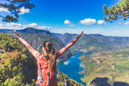 Rear view of young hiker on top of a mountain with scenic view of canyon river landscape. Freedom concept.の写真素材