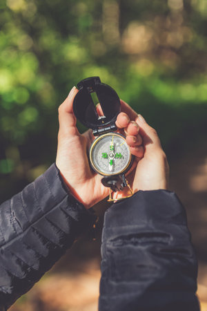 Hiker traveler using compass in nature. Tourist girl trying to find her way out of the forest.の写真素材