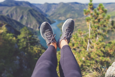 Woman hiker legs with sports shoes against beautiful valley and hills in the background. Healthy lifestyle and nature concepts.の写真素材