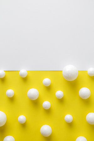 Beer bubbles and foam made of styrofoam balls on white and yellow paper minimal creative drink background. Space for copy.の写真素材