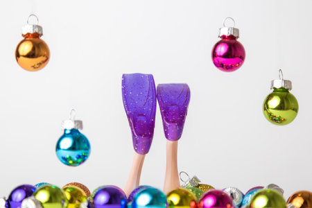 Doll diver feet with flippers diving into colorful baubles minimal creative christmas holiday...