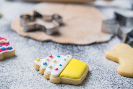 Close op of gingerbread cookie in form of muffin on table with molds, dough and rolling pin in the background. Sweet food preparation concept.の写真素材
