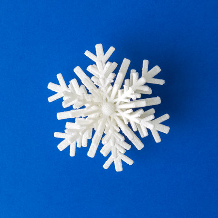 Flat lay of Christmas snowflake decoration on classic blue background minimal creative concept.