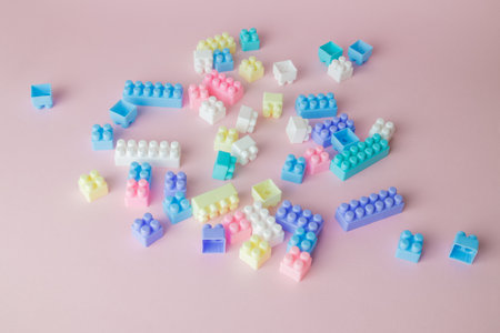 Plastic building blocks toy on pastel pink background minimal creative concept.