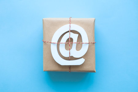 Flat lay of wrapped package with email symbol isolated on pastel blue background minimal creative...