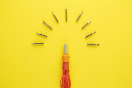 Flat lay of screwdriver with heads on yellow background minimal tool creative concept.