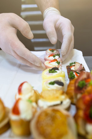 Close up of man hands putting catering snacks on plate.の写真素材