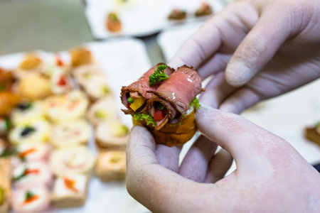 Close up of chef hands holding canape while preparing buffet meal at restaurant.の写真素材
