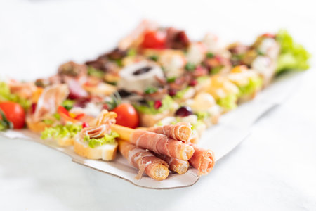 Close up of bread sticks grissini with prosciutto ham on plate with canape appetizers catering concept.の写真素材