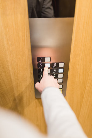 Close up of businessman pressing button in modern elevator.