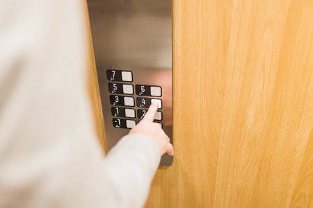 Close up of businessman pressing button in modern wooden and steel elevator.の写真素材