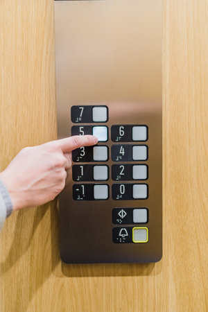 Forefinger pressing fifth floor button in the elevator. Space for copy.の写真素材