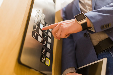 Close up of businessman pressing third floor control panel button in elevator.の写真素材