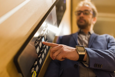 Man pressing modern elevator button with his forefinger.