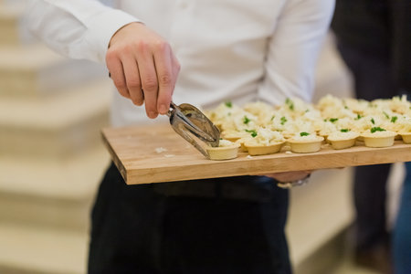 Waiter serving vegetarian canapes at celebration event.