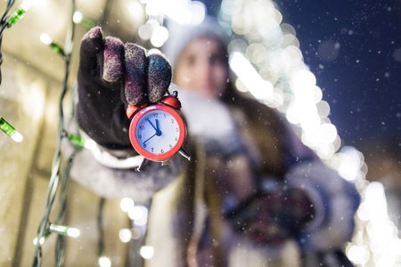 Young female showing alarm clock. Almost midnight time to celebrate holiday concept.の写真素材