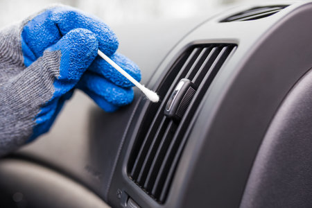Close up of man hand cleaning car air conditioning vent grill with cotton swab.の写真素材
