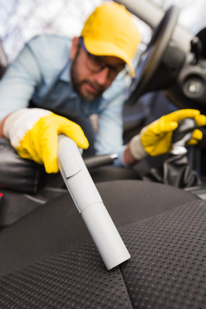 Close up of man cleaning car seat with vacuum cleaner.の写真素材
