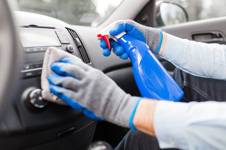 Close up of man hands using microfiber cloth and spray bottle while cleaning car interior.の写真素材