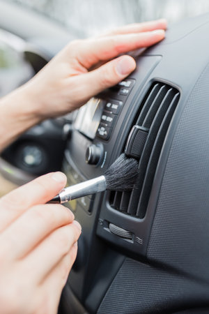 Worker cleaning automobile air conditioner vent grill with brush, closeup. Car wash serviceの写真素材