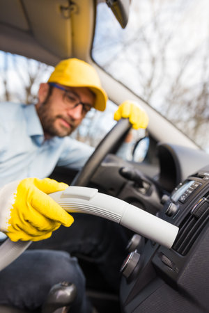 Professional handyman vacuuming car interior by using vacuum cleaner.の写真素材