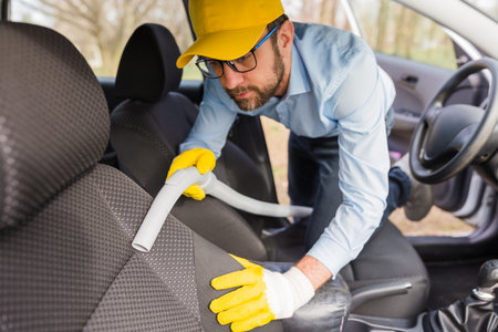 Man worker using vacuum cleaner in carの写真素材