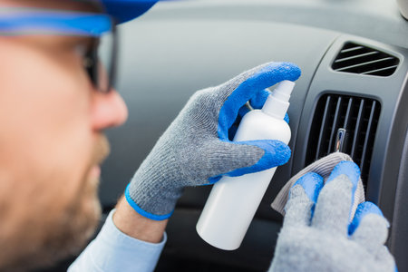 Man cleansing car vent grille air duct and spraying with disinfection liquid.の写真素材