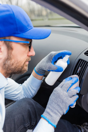 Professional worker using disinfectant and microfiber cloth to clean car interior.の写真素材