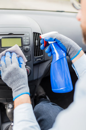 Cleaning car dashboard concept. Car wash worker using disinfectant and microfiber cloth.の写真素材