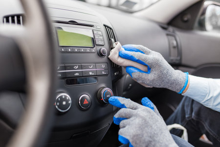 Worker cleaning car interior, pressing ac button and holding microfiber cloth.の写真素材