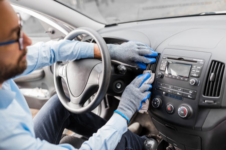 Car wash worker maintaining and detailing car interior console shine by using microfiber cloth. Cleaning salon concept.の写真素材