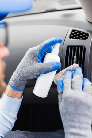 Professional worker using disinfectant and microfiber cloth to clean car interior.の写真素材