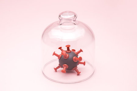 Coronavirus cell isolated under glass cover against pastel pink background minimal creative covid-19 pandemic creative concept.の写真素材