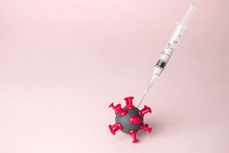 Syringe with liquid medicine shot to corona virus cell minimal creative concept. Space for copy.