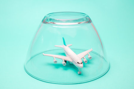 Airplane in isolation quarantine under glass bowl, minimal creative global travel problems during corona virus pandemic.の写真素材