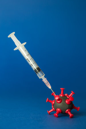 Covid-19 vaccination abstract made of syringe and virus cell against dark blue background.の写真素材