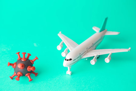 Travel restrictions concept made of coronavirus cell and airplane toy on pastel blue background.の写真素材