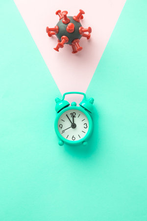 Time is running out. Coronavirus find the cure creative concept made of covid-19 cell symbol and alarm clock.の写真素材